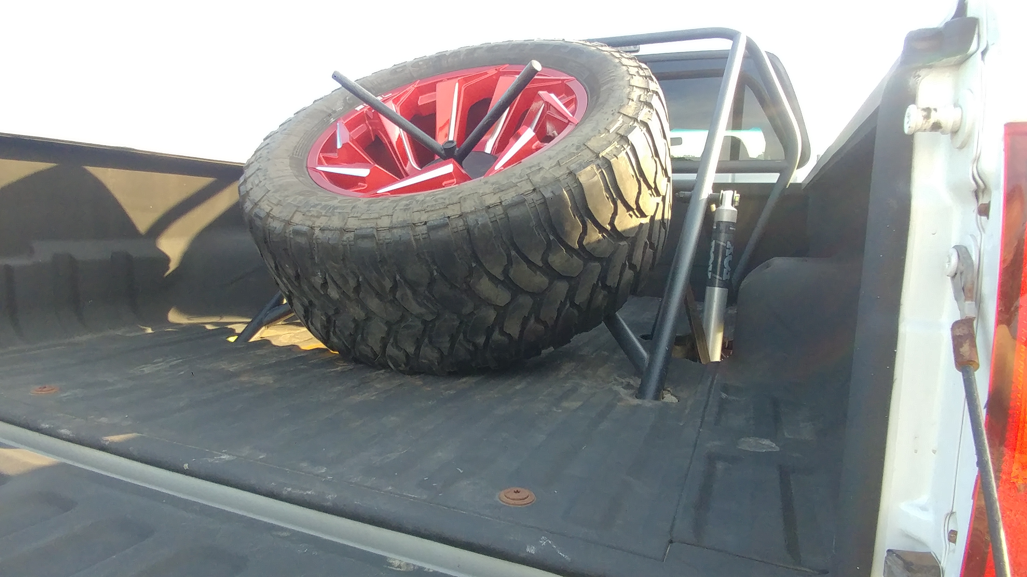 Full size spare wheel and tire strapped in the bed
